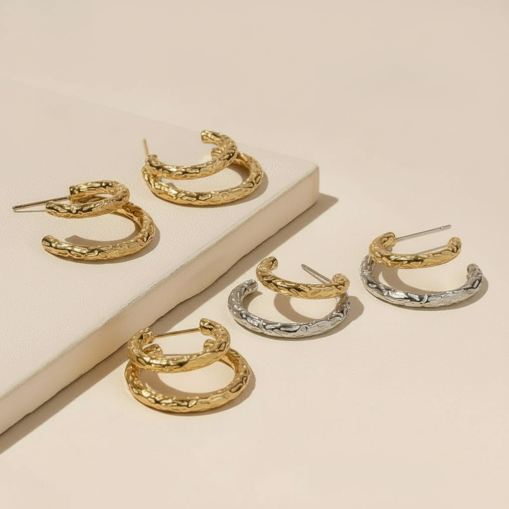 Gold and silver hoop earrings on a beige surface