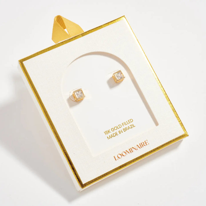 Gold earrings in a LOOMIVNIRE box on a light gray background