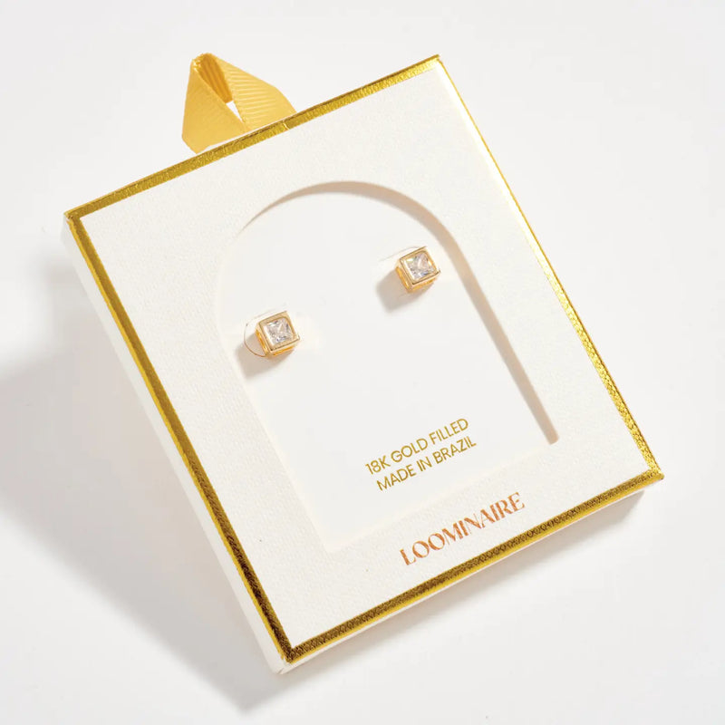 Gold earrings in a LOOMIVNIRE box on a light gray background