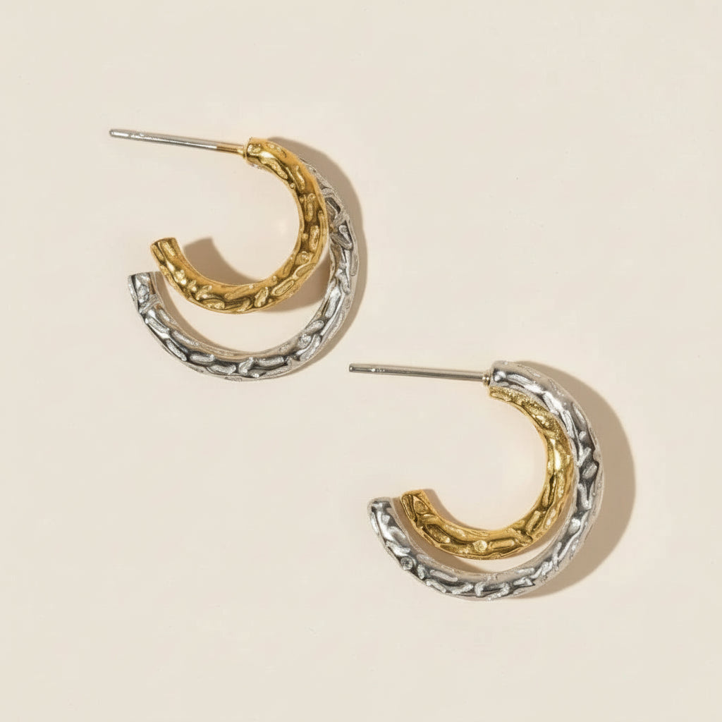 Pair of gold and silver hoop earrings on a beige background