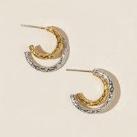 Pair of gold and silver hoop earrings on a beige background