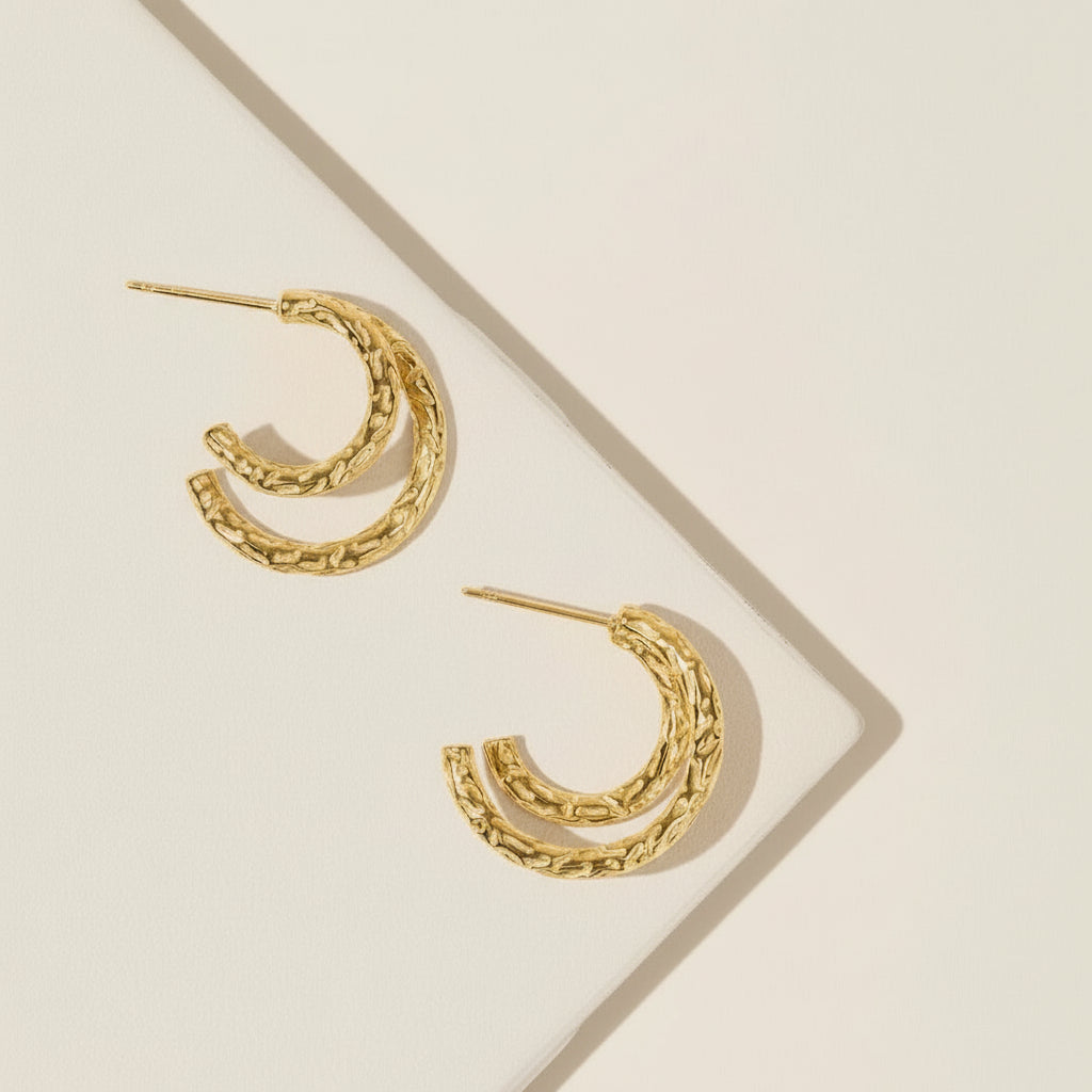 Gold hoop earrings on a beige background