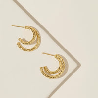 Gold hoop earrings on a beige background