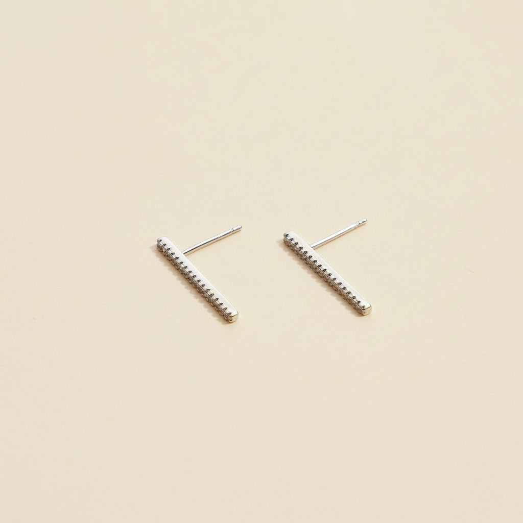 Pair of silver bar earrings on a beige background