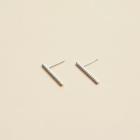 Pair of silver bar earrings on a beige background